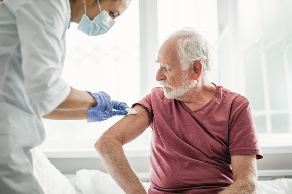 Älterer Mann erhält von einer Ärztin eine Impfung in den Oberarm