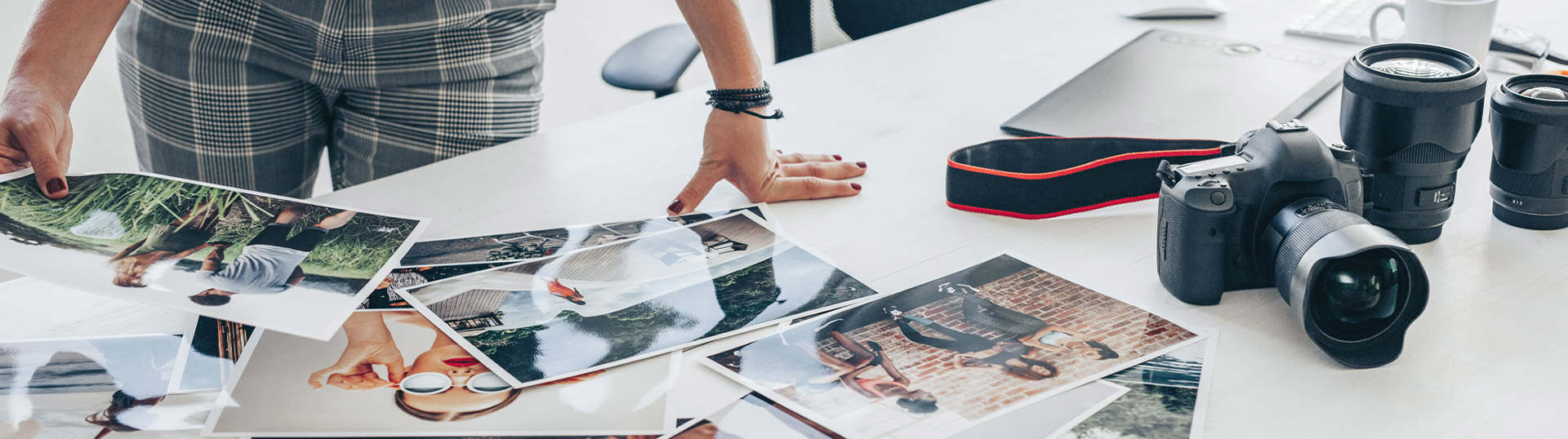 Bildausschnitt: Fotografin sichtet auf einem Tisch Fotos, Kamera liegt daneben