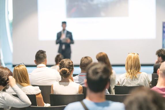 männlicher Sprecher, der einen Vortrag in einem Konferenzsaal bei einem geschäftlichen Event hält 