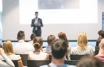 männlicher Sprecher, der einen Vortrag in einem Konferenzsaal bei einem geschäftlichen Event hält 