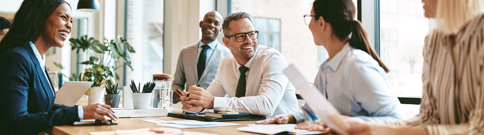 Fünf Kolleg*innen sitzen an einem Besprechungstisch in einem modernen Büro