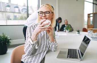 junge Frau sitzt mit einer Kaffeetasse vor einem Notebook