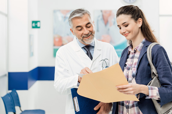 Arzt erklärt einer jungen Patientin die Unterlagen, die sie in der Hand hält