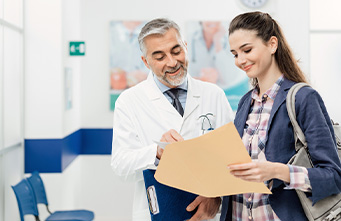 Arzt erklärt einer jungen Patientin die Unterlagen, die sie in der Hand hält