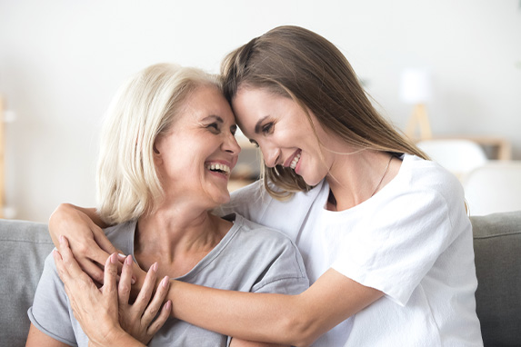 Mutter und Tochter nehmen sich in den Arm und lächeln einander an