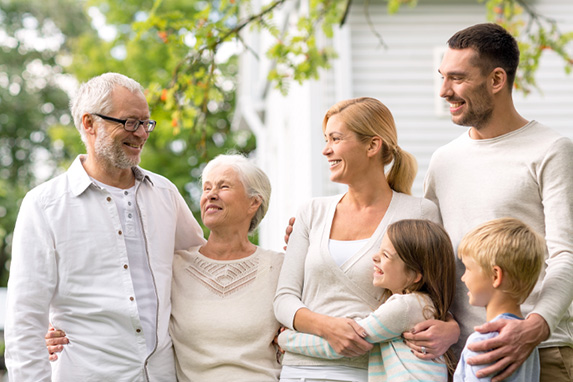 Lächelnde Familie (drei Generationen) vor dem Haus