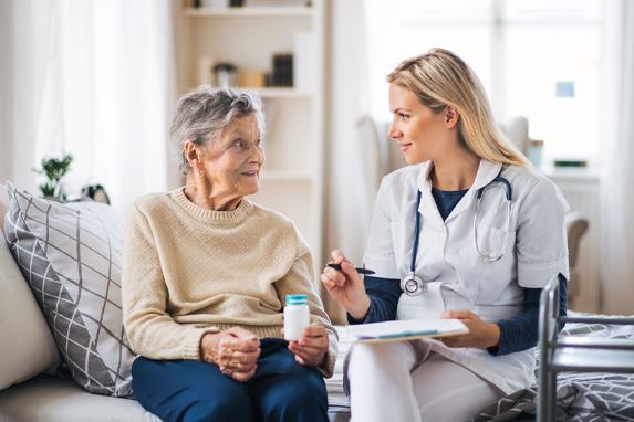 weibliche Pflegekraft erkl&auml;rt einer &auml;lteren Dame wie man Medikamente ein nimmt