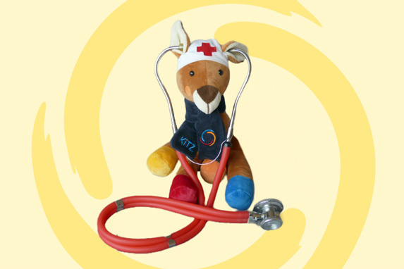 Stofftier Hopps (Hase) trägt eine Mütze mit einem roten Kreuz und hat ein Stethoskop um den Hals