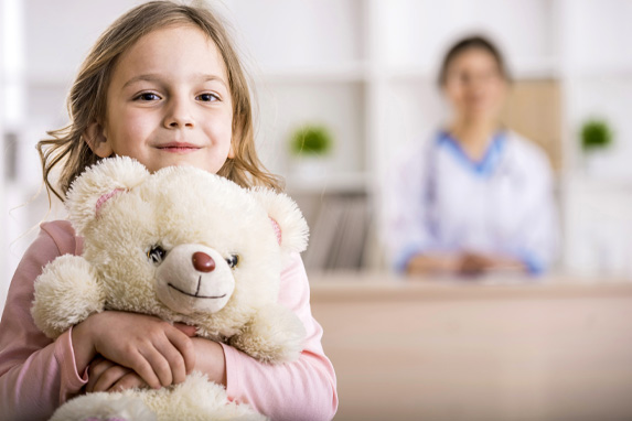 Kleines Mädchen mit einem weißen Teddy im Arm