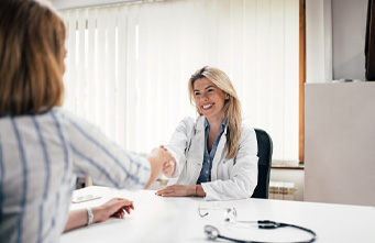 Lächelnde junge Ärztin gibt einer Patientin die Hand